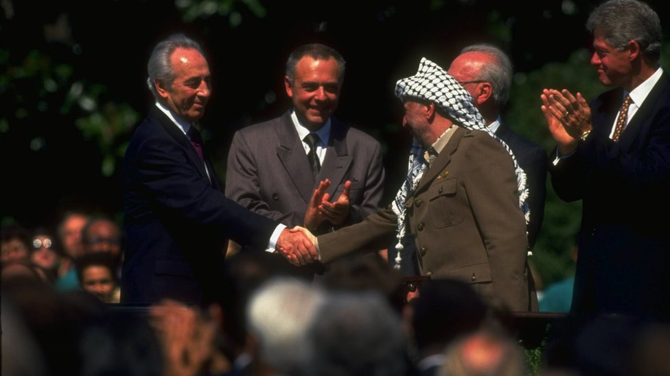 Lider PLO Jaser Arafat (desno) rukuje se sa izraelskim ministrom spoljnih poslova imonom Peresom na potpisivanju Sporazuma iz Osla dok ameriki predsednik Bil Klinton (krajnje desno) aplaudira/Getty Images