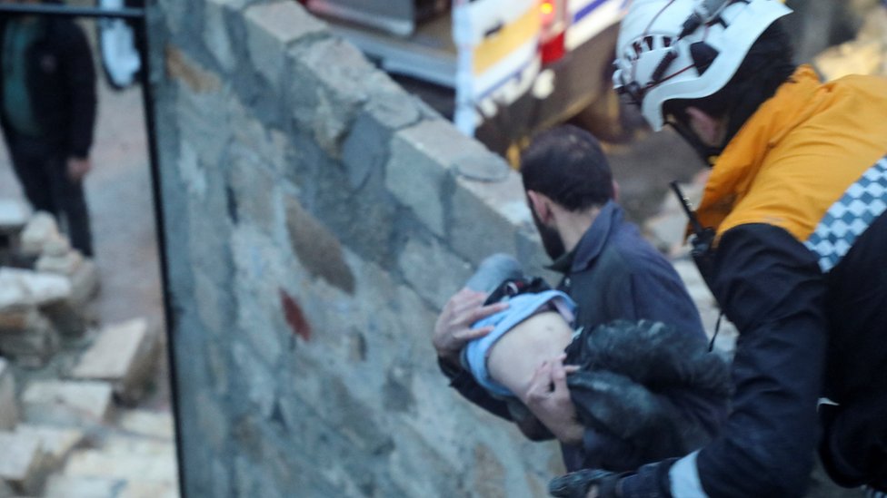 Muškarac nosi dete u sirijskom gradu Azazu/REUTERS/Mahmoud Hassano